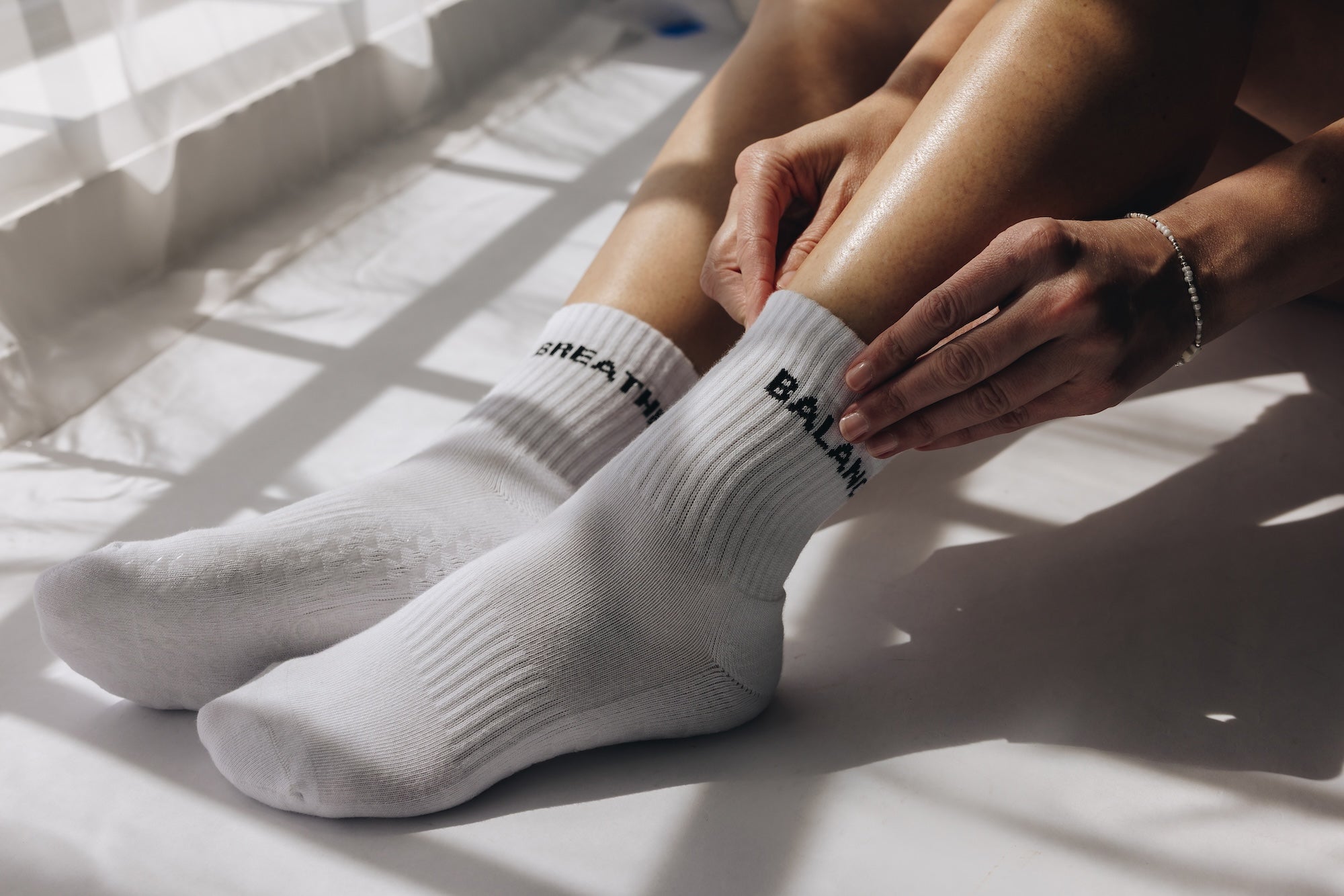 White grip socks with text worn by a person sitting on a light-colored surface.