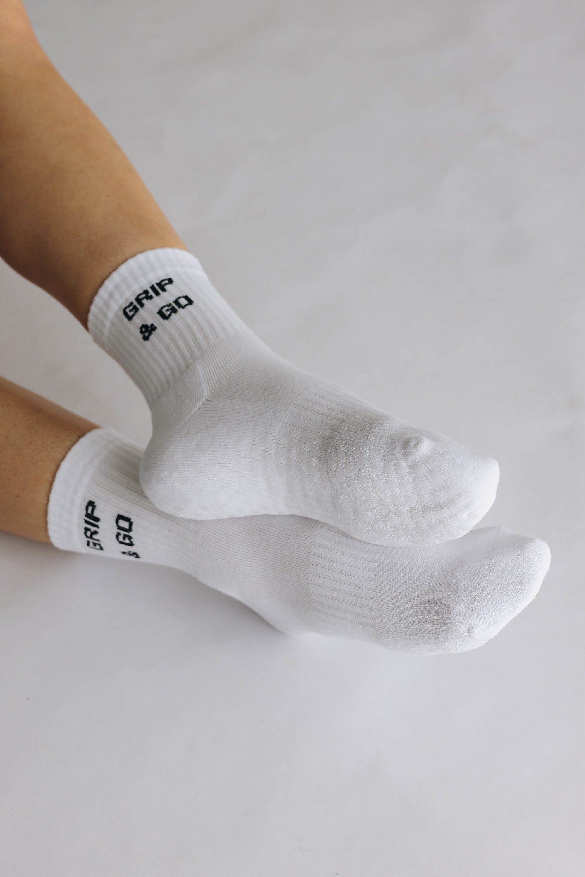 White grip socks with 'GRIP & GO' branding on a light gray background