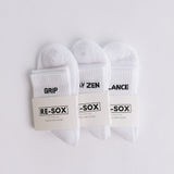 Three white ribbed pairs of grip socks featuring slogans Breathe/Balance, Stay Zen and Grip & Go. packaged with RE-SOX sock card. 