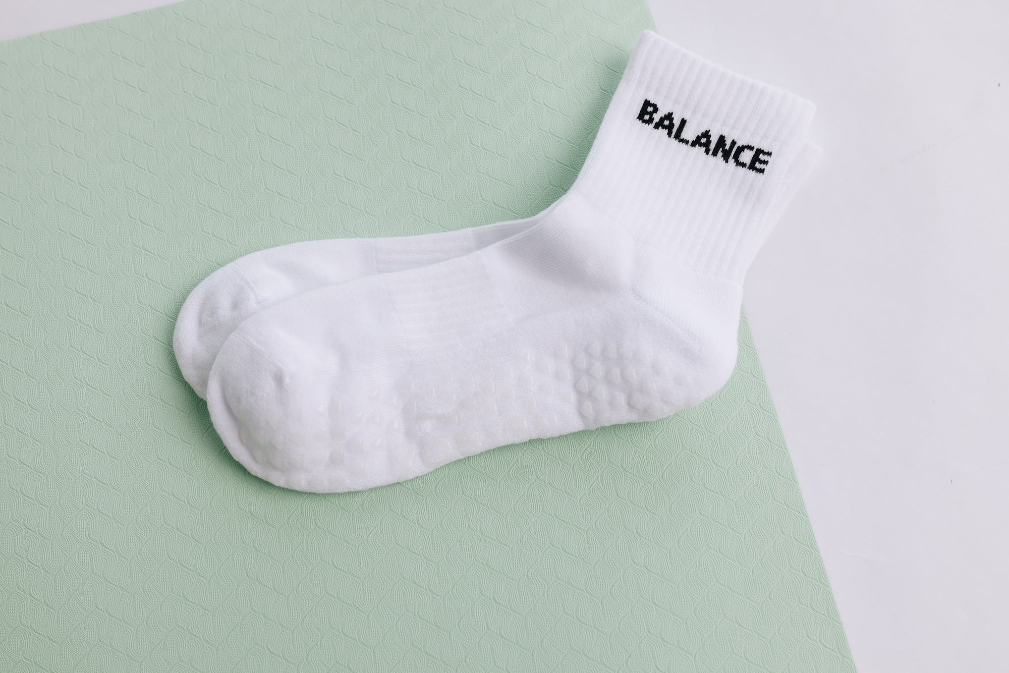 White grip sock with 'BALANCE' text on a light green background