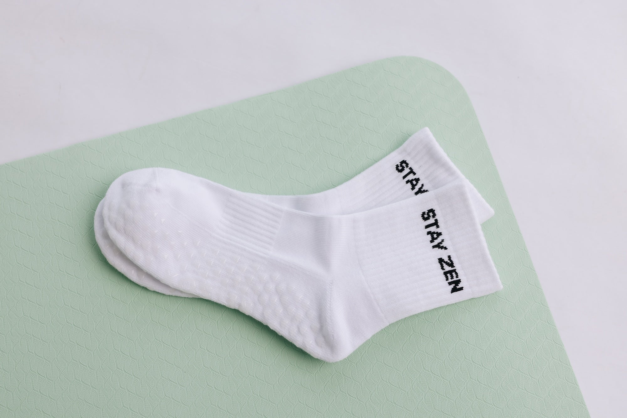 White grip sock with 'STAY ZEN' text on a light green surface