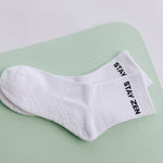 White grip sock with 'STAY ZEN' text on a light green surface