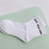 White grip sock with 'STAY ZEN' text on a light green surface