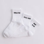 Three white ribbed pairs of grip socks featuring slogans Breathe/Balance, Stay Zen and Grip & Go