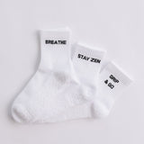 Three white ribbed pairs of grip socks featuring slogans Breathe/Balance, Stay Zen and Grip & Go