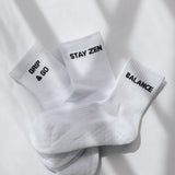 Three white ribbed pairs of grip socks featuring slogans Breathe/Balance, Stay Zen and Grip & Go