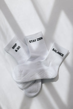 Three white ribbed pairs of grip socks featuring slogans Breathe/Balance, Stay Zen and Grip & Go