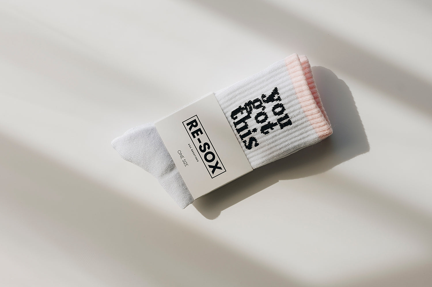 A pair of white ribbed crew socks with the text 'you got this' printed on the side, packaged in white sock card with RE-SOX logo